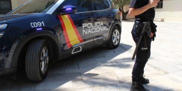 Agente de la Policía Nacional junto a un coche patrulla