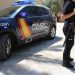 Agente de la Policía Nacional junto a un coche patrulla