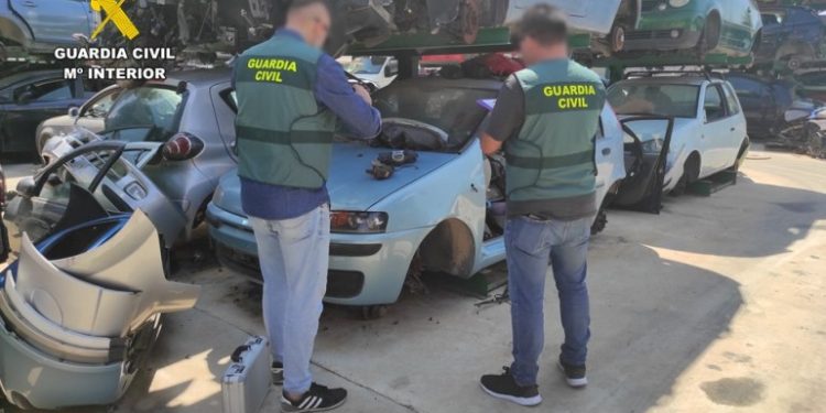 Dos agentes de la Guardia Civil inspeccionan un desguace