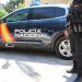 Agente de la Policía Nacional junto a un coche patrulla