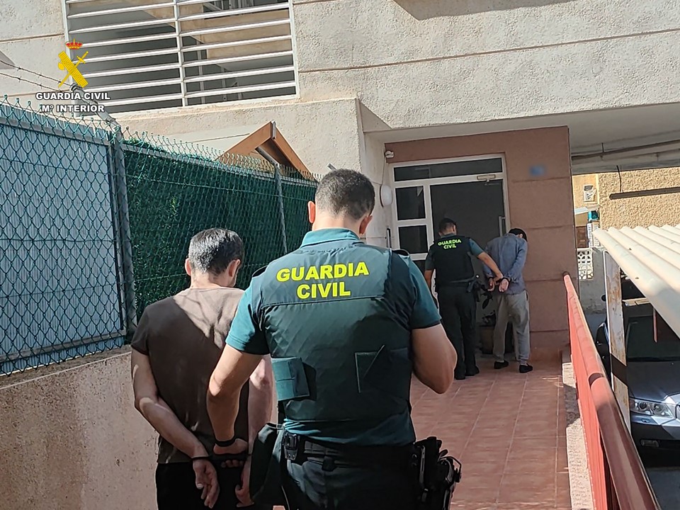 Dos agentes de la Guardia Civil conducen a dos de los detenidos al cuartel