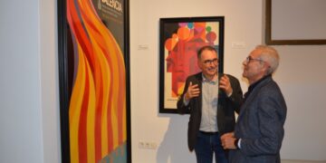 Santiago Ballester y Gil Manuel Hernández, ante uno de los carteles de la exposición ‘Esclats de Modernitat Gràfica’