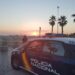 Agente de la Policía Nacional y coche patrulla en el paseo marítimo de Gandia