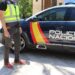 Agente junto a un coche patrulla de la Policía Nacional