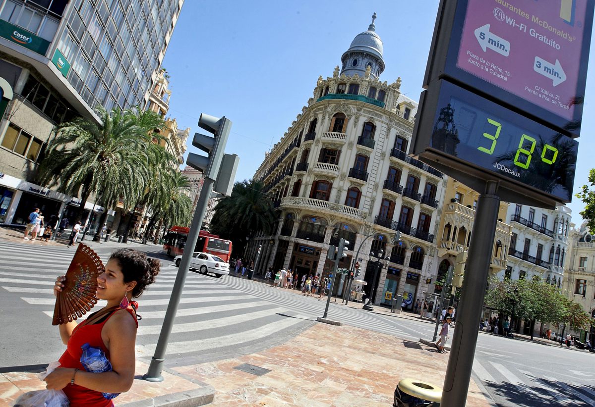 Una joven se abanica ante un termómetro que marca 38 grados. EFE/Manuel Bruque/Archivo