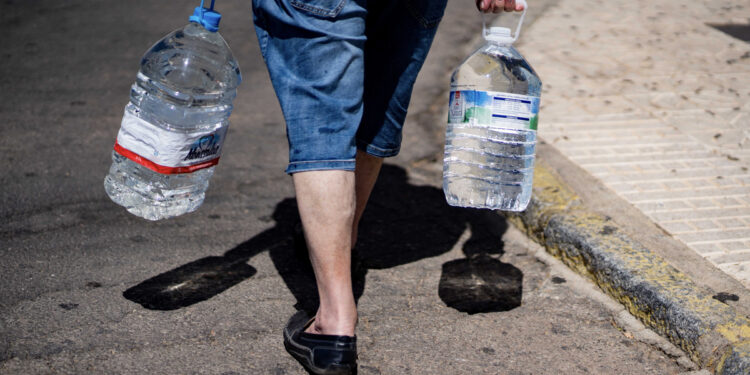 Un hombre lleva dos garrafas de agua. EFE/Rafa Alcaide/Archivo