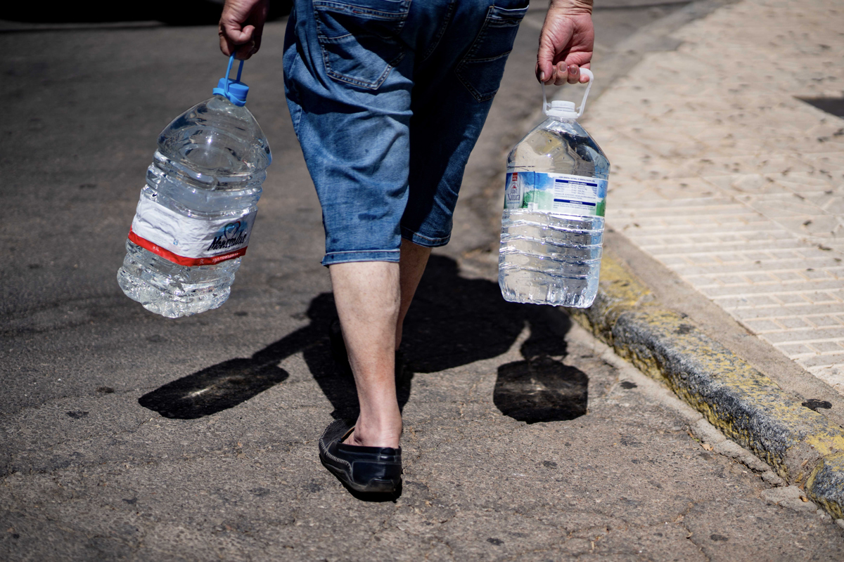 Un hombre lleva dos garrafas de agua. EFE/Rafa Alcaide/Archivo